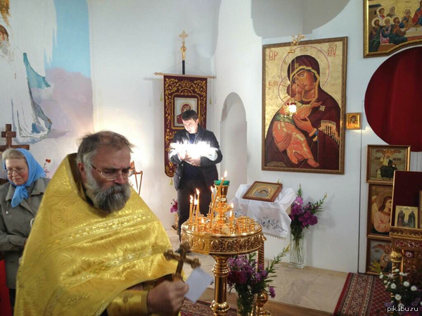 фотография с недавней Литургии, запечатлела сияющего младенца после причастия и священника с нимбом на голове.