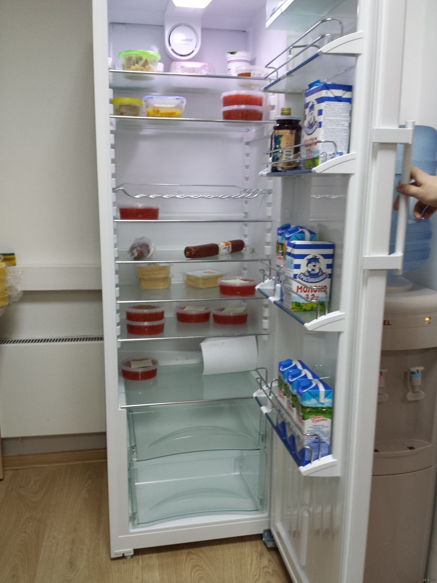Открытый холодильник с продуктами полупустой